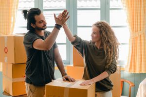 A couple doing a high-five next to cardboard boxes